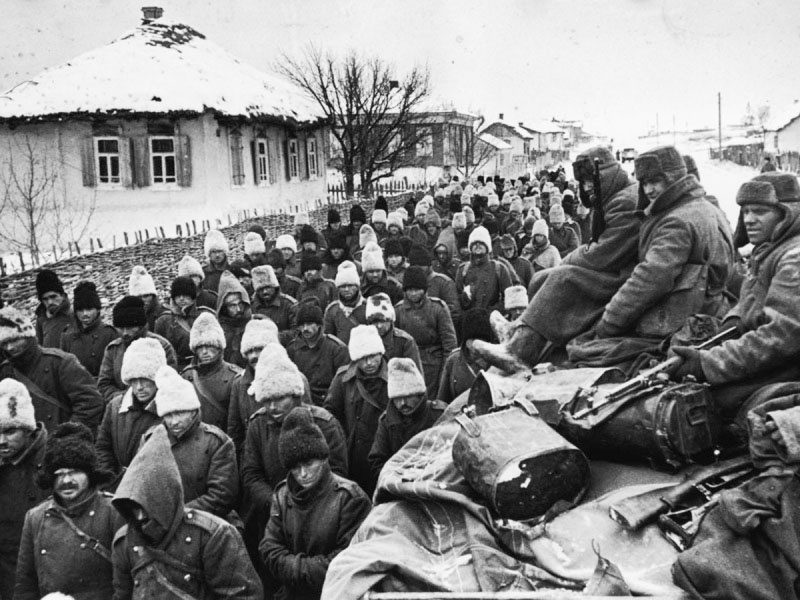 Колонна румынских солдат, захваченных под Сталинградом, движется мимо грузовика с красноармейцами.